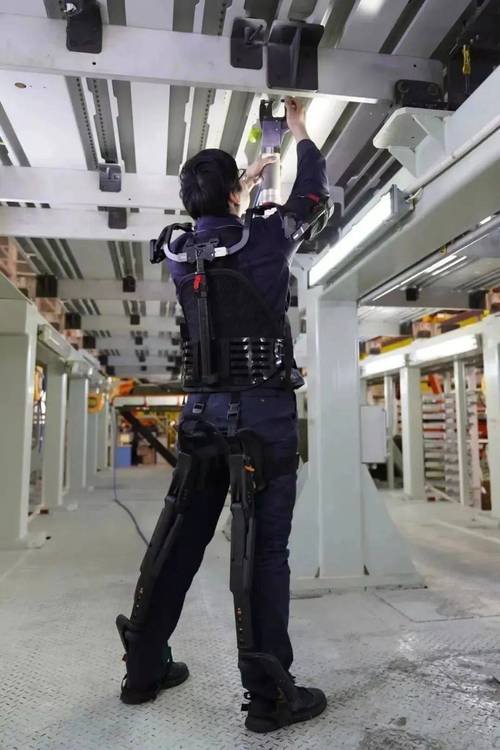 工人在工厂车间穿戴外骨骼搬运金属件