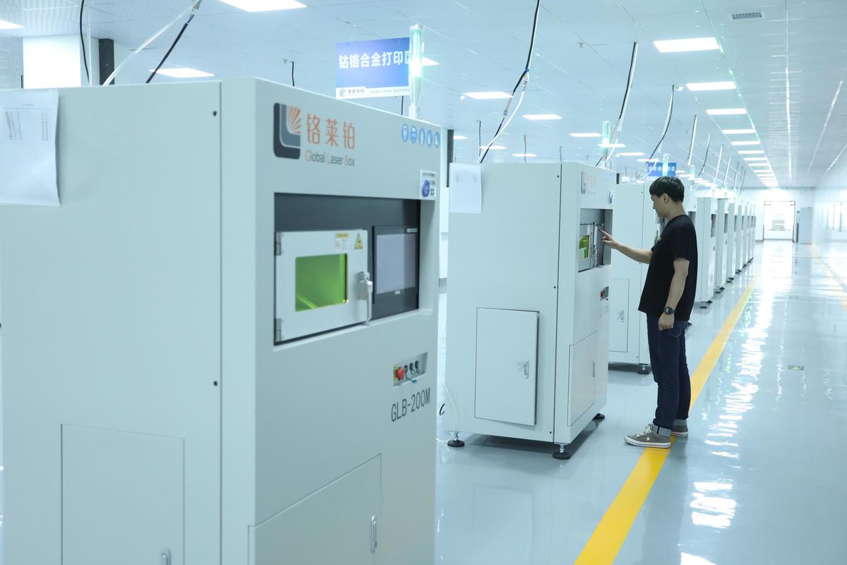 工业级金属3D打印机在车间内运行的场景,可见粉床和激光光路