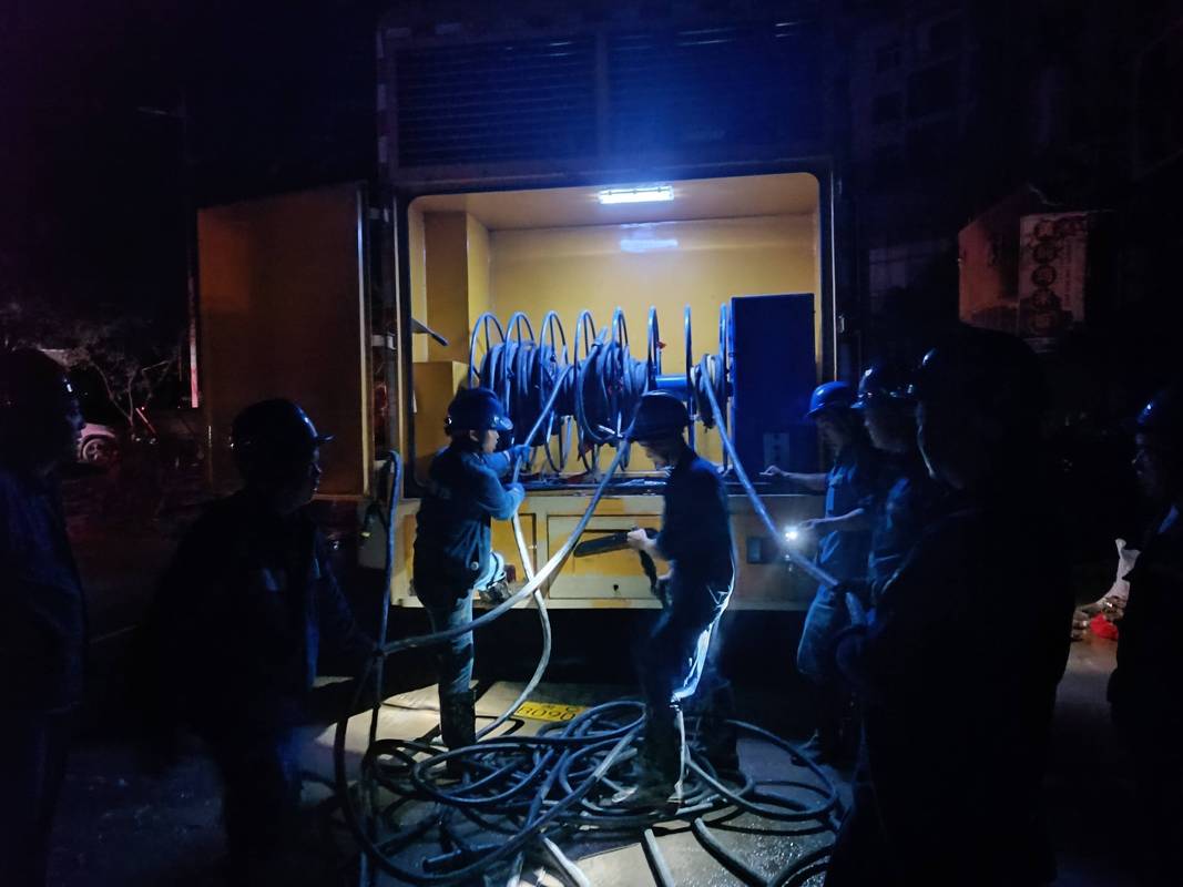 深夜工厂设备故障抢修现场,工人打着手电筒检查控制柜